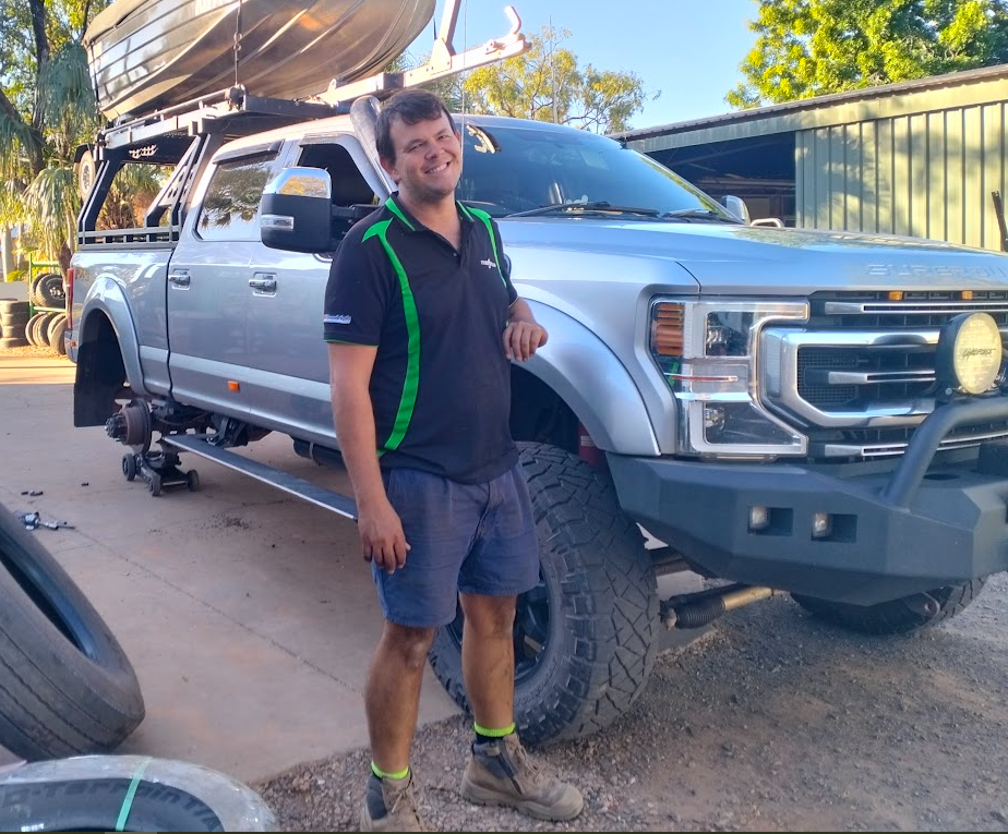 Technician standing beside a LandCruiser on the hoist in the Tyreplus Kununurra workshop